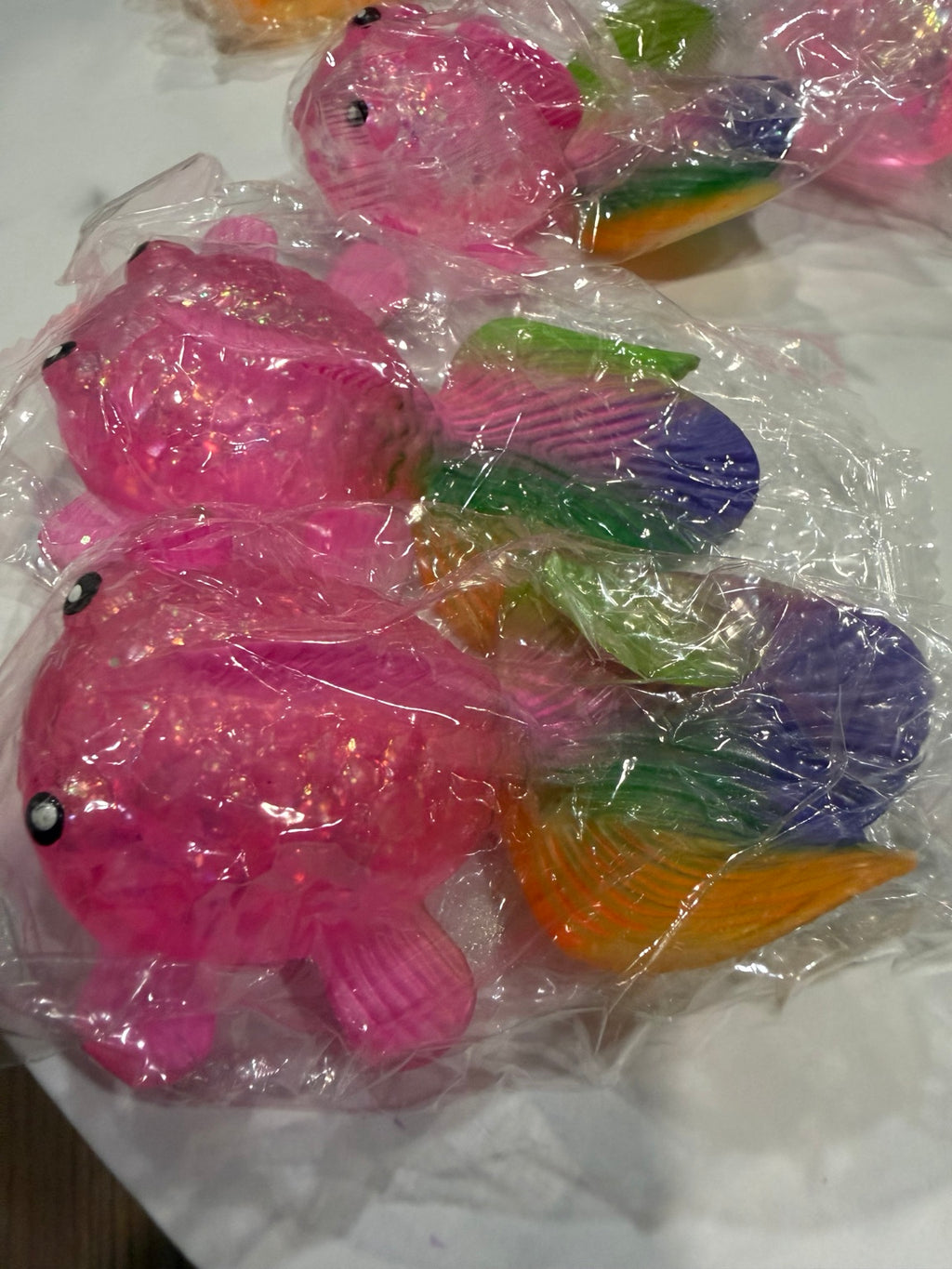 Several pink glitter fish squishies with multicolor tails